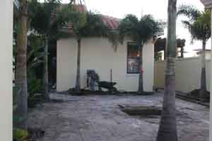 Orlando landscaper hand digging a french drain near a house for drainage